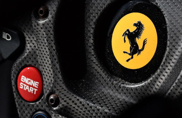 Ferrari race car steering wheel with horse graphic on yellow background, button labeled Engine Start.